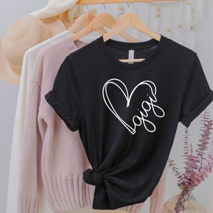 May include: Black t-shirt with a white heart design and the word "Gigi" written inside the heart.