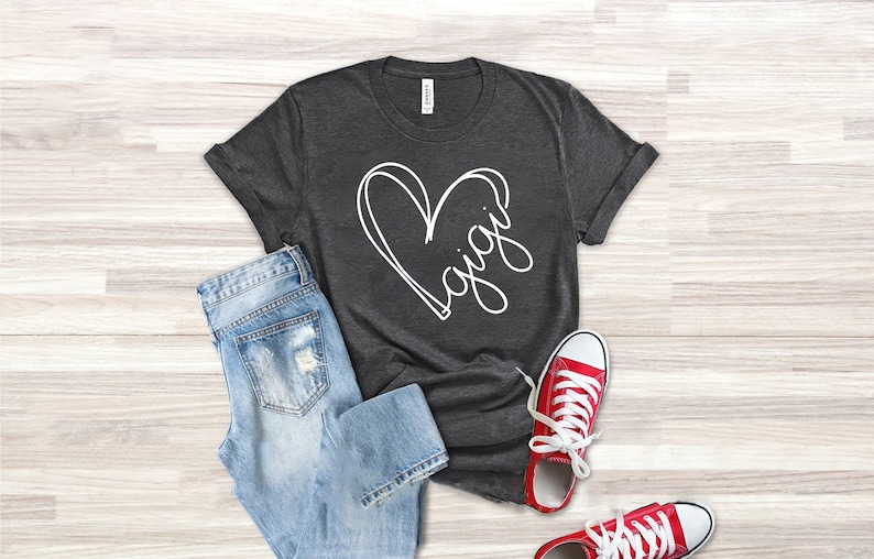 May include: A dark gray t-shirt with a white heart design and the word "Gigi" written inside the heart.