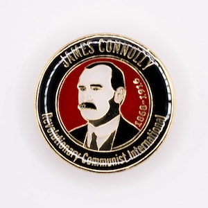Può includere: Uno spillo dorato con un'immagine rossa, bianca e nera di James Connolly, un leader socialista rivoluzionario. Lo spillo riporta la scritta "James Connolly 1868-1916 Revolutionary Communist International".