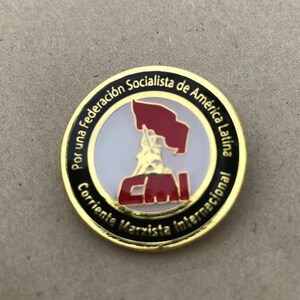 May include: A gold-colored pin with a black border and a white center. The center features a red flag and a red and white logo that says "CMI". The text around the border reads "Federación Socialista de América Latina por una Corriente Marxista Internacional".
