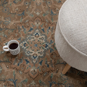 A Close-up of vintage persian rug, Warm brown background with muted blue floral and medallion details. 7.5 x 9.9 feet