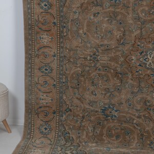 A Close-up of vintage persian rug, Warm brown background with muted blue floral and medallion details. 7.5 x 9.9 feet