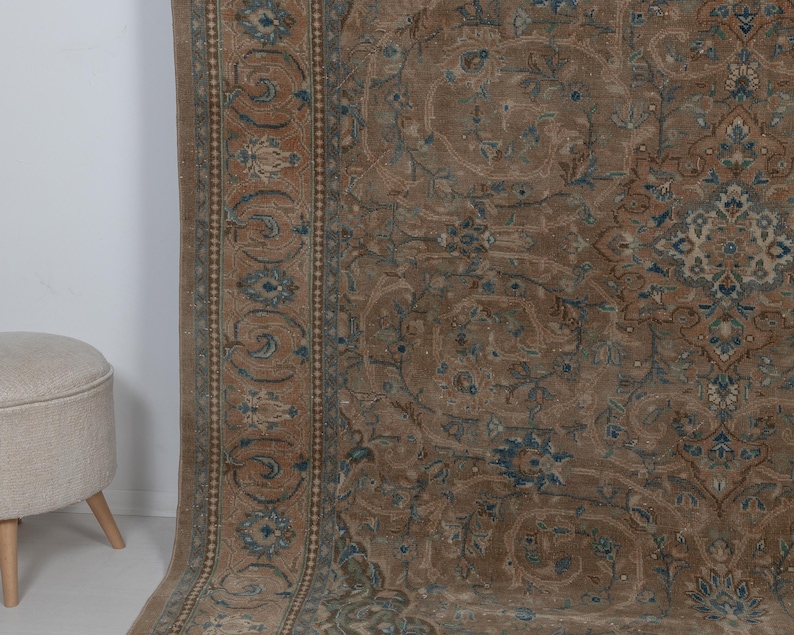 A Close-up of vintage persian rug, Warm brown background with muted blue floral and medallion details. 7.5 x 9.9 feet