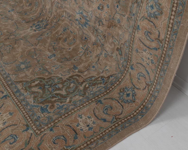 A Close-up of vintage persian rug, Warm brown background with muted blue floral and medallion details. 7.5 x 9.9 feet