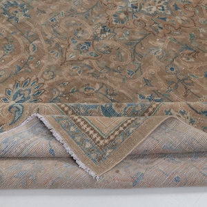 A Close-up of vintage persian rug, Warm brown background with muted blue floral and medallion details. 7.5 x 9.9 feet