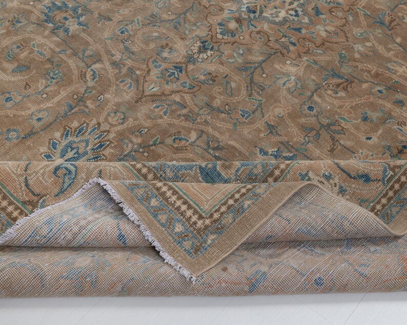 A Close-up of vintage persian rug, Warm brown background with muted blue floral and medallion details. 7.5 x 9.9 feet