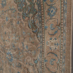 A Close-up of vintage persian rug, Warm brown background with muted blue floral and medallion details. 7.5 x 9.9 feet