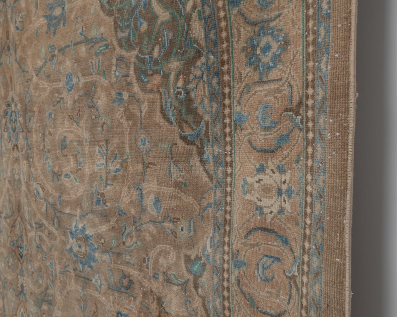 A Close-up of vintage persian rug, Warm brown background with muted blue floral and medallion details. 7.5 x 9.9 feet