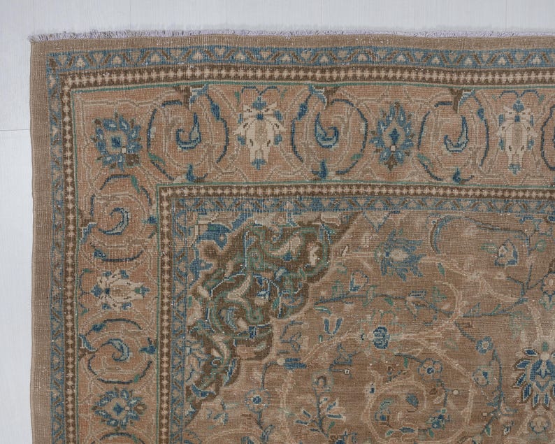 A Close-up of vintage persian rug, Warm brown background with muted blue floral and medallion details. 7.5 x 9.9 feet