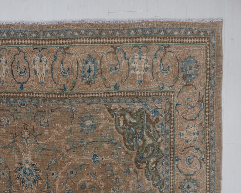 A Close-up of vintage persian rug, Warm brown background with muted blue floral and medallion details. 7.5 x 9.9 feet
