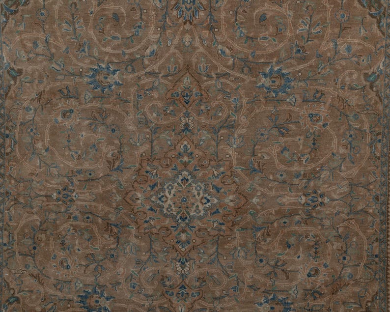 A Close-up of vintage persian rug, Warm brown background with muted blue floral and medallion details. 7.5 x 9.9 feet