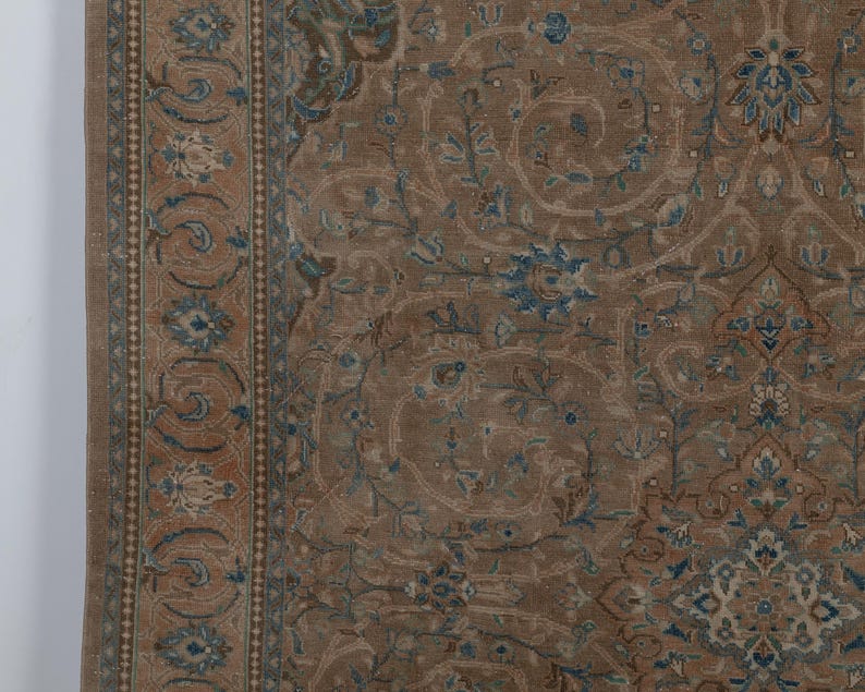 A Close-up of vintage persian rug, Warm brown background with muted blue floral and medallion details. 7.5 x 9.9 feet