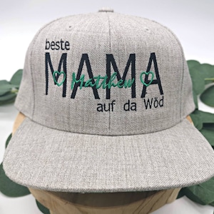 Könnte beinhalten: Graue Baseballkappe mit schwarzer Stickerei, die "beste MAMA Matthew auf da Wöd" mit grünen Herzen lautet.