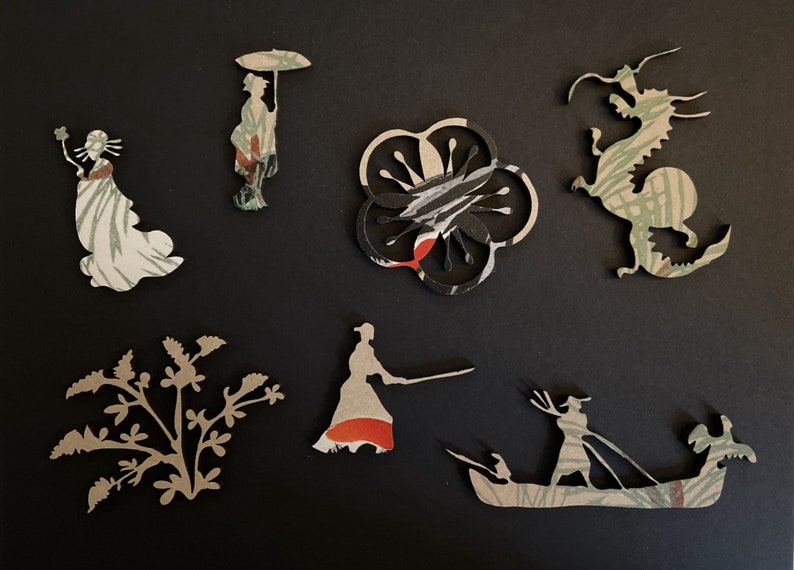 Op de afbeelding: Een verzameling van acht papieren uitsnijdingen met verschillende ontwerpen, waaronder een draak, een bloem, een persoon met een paraplu, een persoon met een bloem, een persoon met een zwaard, een persoon in een boot en een plant. De uitsnijdingen zijn gemaakt van gepatroneerd papier in de kleuren groen, wit, zwart en rood.