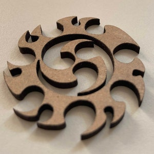 Op de afbeelding: Een bruine houten uitsnijding van een gestileerd abstract ontwerp met een spiraalpatroon.