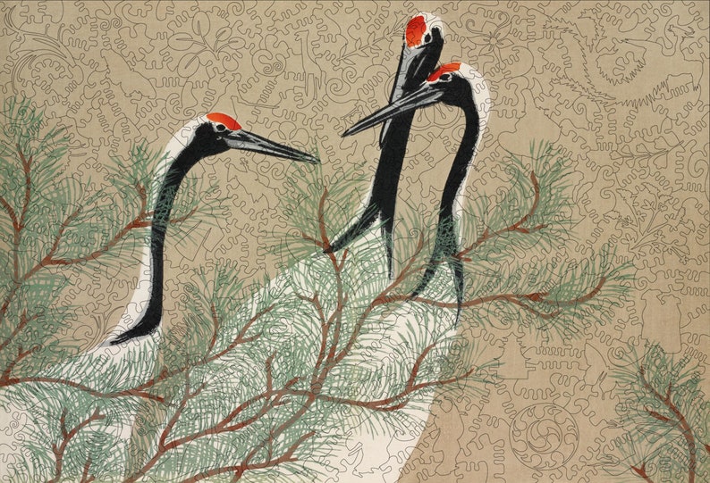 Op de afbeelding: Drie witte kranen met zwarte nek en rode kronen staan in een dennenboom met groene naalden. De kranen kijken in verschillende richtingen. De achtergrond is lichtbruin met een draaiend patroon.