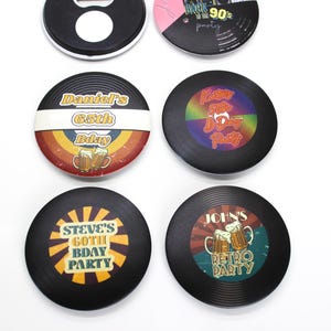 Può includere: Sei sottobicchieri rotondi in vinile nero a forma di disco con disegni e testo colorati. I sottobicchieri presentano temi di festa di compleanno con testo come "Daniel's 65th Bday", "Steve's Goth Bday Party", "John's Retro Party" e "Rock the 90's Party".