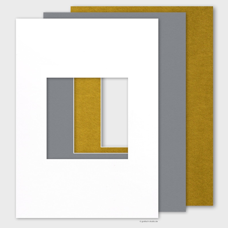 May include: A white mat with a double window opening. The inner window is gold and the outer window is gray. The mat is designed to be used for framing a picture or artwork.