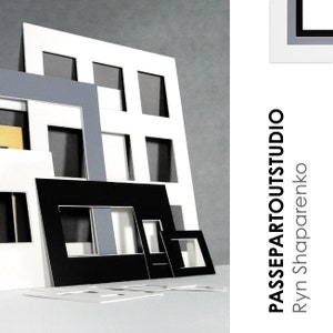 May include: A collection of white, black, and gray mat boards with different sized openings. The mat boards are stacked on top of each other and arranged in a staggered pattern. The text "PASSEPARTOUTSTUDIO" and "Ryn Shaparenko" is printed on the right side of the image.