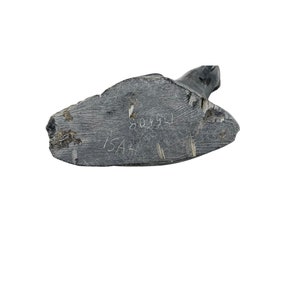 May include: Close-up of the bottom of a dark gray stone sculpture. The sculpture is signed "ISAK" and dated "8093".