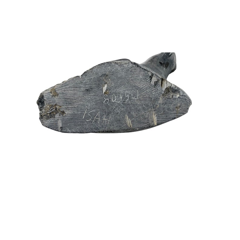 May include: Close-up of the bottom of a dark gray stone sculpture. The sculpture is signed "ISAK" and dated "8093".