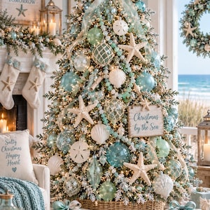 Puede incluir: Un &aacute;rbol de Navidad decorado con adornos de cristal azul claro y transparente, estrellas de mar blancas, d&oacute;lares de arena y cuentas marinas. Un letrero de madera dice Christmas by the Sea. La punta tiene una estrella de mar grande.