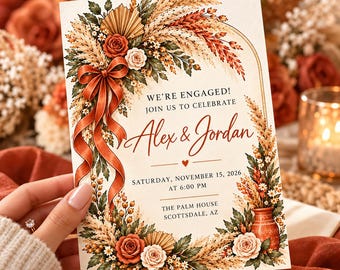 May include: An engagement invitation card featuring an arched floral border of pampas grass, dried wheat, and roses in rust and cream tones. A rust-colored ribbon bow adorns the left side. Text reads: WE'RE ENGAGED! JOIN US TO CELEBRATE Alex & Jordan SATURDAY, NOVEMBER 15, 2026 AT 6:00 PM THE PALM HOUSE SCOTTSDALE, AZ.