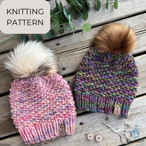 May include: Knitting pattern for two colorful hats with faux fur pom poms. The hats are made with a textured stitch and have a brown leather label with the text "Knitting Pattern" on it.