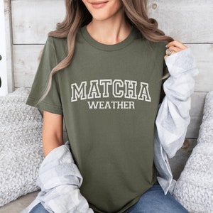 May include: A green t-shirt with the text "MATCHA WEATHER" in white block letters.