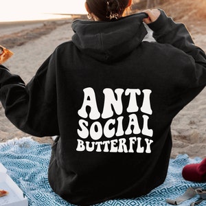 May include: Black hoodie with the text "ANTI SOCIAL BUTTERFLY" in white, retro-style font. The hoodie is a casual garment, perfect for everyday wear. The image shows the back of the hoodie.
