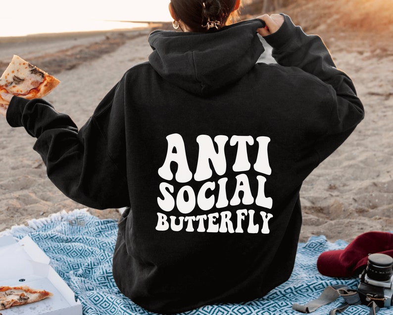 May include: Black hoodie with the text "ANTI SOCIAL BUTTERFLY" in white, retro-style font. The hoodie is a casual garment, perfect for everyday wear. The image shows the back of the hoodie.