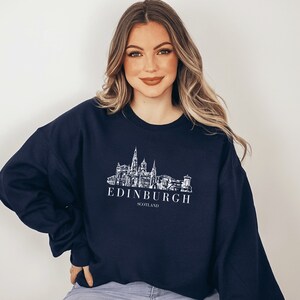May include: A navy blue sweatshirt with a white graphic of the Edinburgh skyline and the text "EDINBURGH SCOTLAND".
