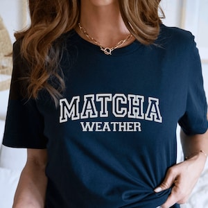 May include: A navy blue t-shirt with white text that reads "MATCHA WEATHER".