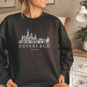 May include: Black sweatshirt with a white graphic of the Edinburgh skyline and the text "EDINBURGH SCOTLAND".