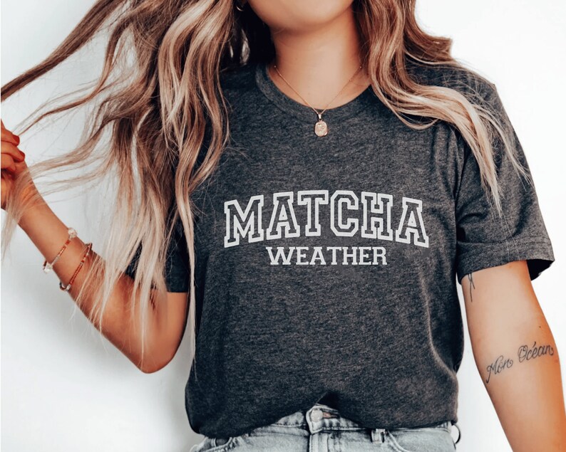 May include: A dark gray t-shirt with white text that reads "MATCHA WEATHER".