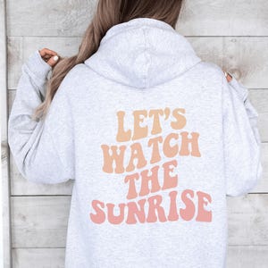 May include: A gray hoodie with a pink and orange graphic that says "Let's watch the sunrise".