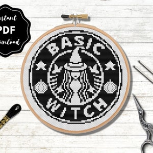 Könnte beinhalten: Schwarzweißes Kreuzstichmuster einer Hexe mit Hut und den Worten "Basic Witch" in einem Kreis. Das Muster befindet sich in einem hölzernen Stickrahmen.