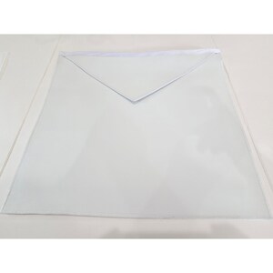 May include: A plain white ceremonial apron featuring a square body and a triangular flap at the top. The garment is constructed from a smooth, solid white material with clean, straight edges and a consistent, uniform color throughout the entire piece.
