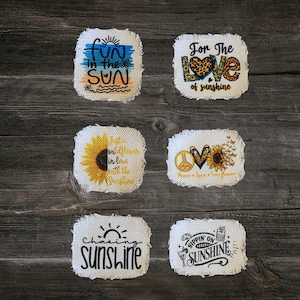 May include: Six handmade fabric coasters with frayed edges. The coasters feature various summer-themed designs with sunflowers, peace signs, hearts, and text. The text on the coasters includes "Fun in the Sun", "For the Love of Sunshine", "Just a Wildflower in Love with the Sunshine", "Peace Love Sunflower", "Chasing Sunshine", and "Sippin' on Sunshine".