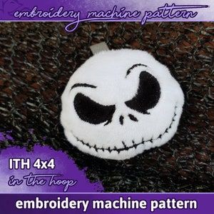 Könnte beinhalten: Ein weißer Plüsch-Jack Skellington-Charakter mit schwarzen gestickten Augen und Mund. Der Plüsch hat die Form eines Kreises und ist 4x4 Zoll groß. Der Text "ITH 4x4 in the hoop" ist in lila Farbe auf lila Hintergrund.