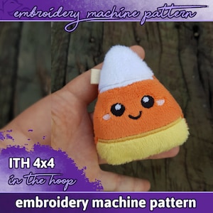 Könnte beinhalten: Stickmuster für eine süße Mais-Plüschfigur. Das Muster ist für einen 4x4-Hoop und enthält Anweisungen zum Herstellen des Spielzeugs im Hoop. Das Spielzeug ist orange, gelb und weiß mit einem lächelnden Gesicht.