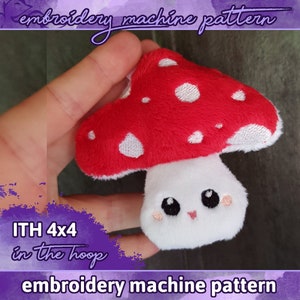 May include: A red and white mushroom with a white face and black eyes. The mushroom is embroidered and is 4x4 inches. The text "ITH 4x4 in the hoop" is in purple on a pink background. The text "embroidery machine pattern" is in purple on a pink background.