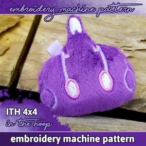 May include: Purple plush embroidery design of a submarine with white and pink details. The design is labeled "ITH 4x4 in the hoop embroidery machine pattern".