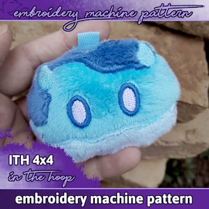 Puede incluir: Un juguete de peluche azul y blanco con forma de personaje de dibujos animados. El juguete está siendo sostenido en una mano. El texto "ITH 4x4 in the hoop" es visible en la imagen. El texto "embroidery machine pattern" es visible en la parte superior e inferior de la imagen.