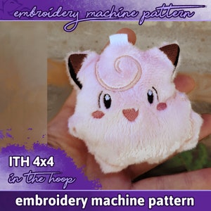 Könnte beinhalten: Rosa Plüschtier mit gestickten Details, das einem Comic-Charakter ähnelt. Das Spielzeug wird in einer Hand gehalten und hat ein Wirbelmuster auf dem Kopf. Der Text "ITH 4x4 in the hoop" und "embroidery machine pattern" ist auf dem Bild sichtbar.
