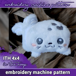 Könnte beinhalten: Gestickter Plüsch-Seehund im Reifen, weiß mit schwarzen Flecken, grauen Augen und rosa Wangen. ITH 4x4 Stickmaschinenmuster.