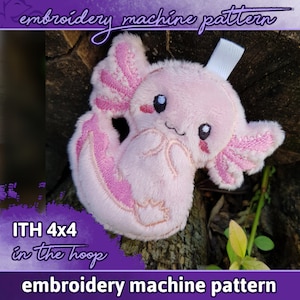 May include: Pink plush axolotl embroidery machine pattern, 4x4 inches, in the hoop. The axolotl has embroidered details, including eyes, a mouth, and gills.