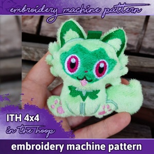 May include: Green plush toy in the shape of a cartoon animal with pink eyes and a pink tongue. The toy is being held in a hand. The text "ITH 4x4 in the hoop" is visible in the image. The text "embroidery machine pattern" is visible at the top and bottom of the image.