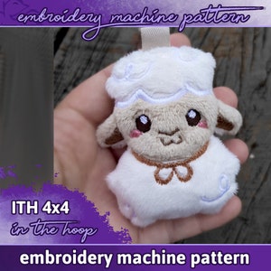 Puede incluir: Cordero de peluche blanco con detalles bordados, incluyendo una nariz marrón, ojos y un collar. El cordero está siendo sostenido en una mano. El texto "ITH 4x4 in the hoop" es visible en la esquina inferior izquierda de la imagen. El texto "embroidery machine pattern" es visible en la parte superior e inferior de la imagen.
