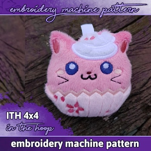 Könnte beinhalten: Rosa Plüschtier in Form einer Katze, die einen weißen Cupcake-Hut trägt. Das Spielzeug ist für die Verwendung mit einer Stickmaschine konzipiert und mit "ITH 4x4 in the hoop embroidery machine pattern" gekennzeichnet.